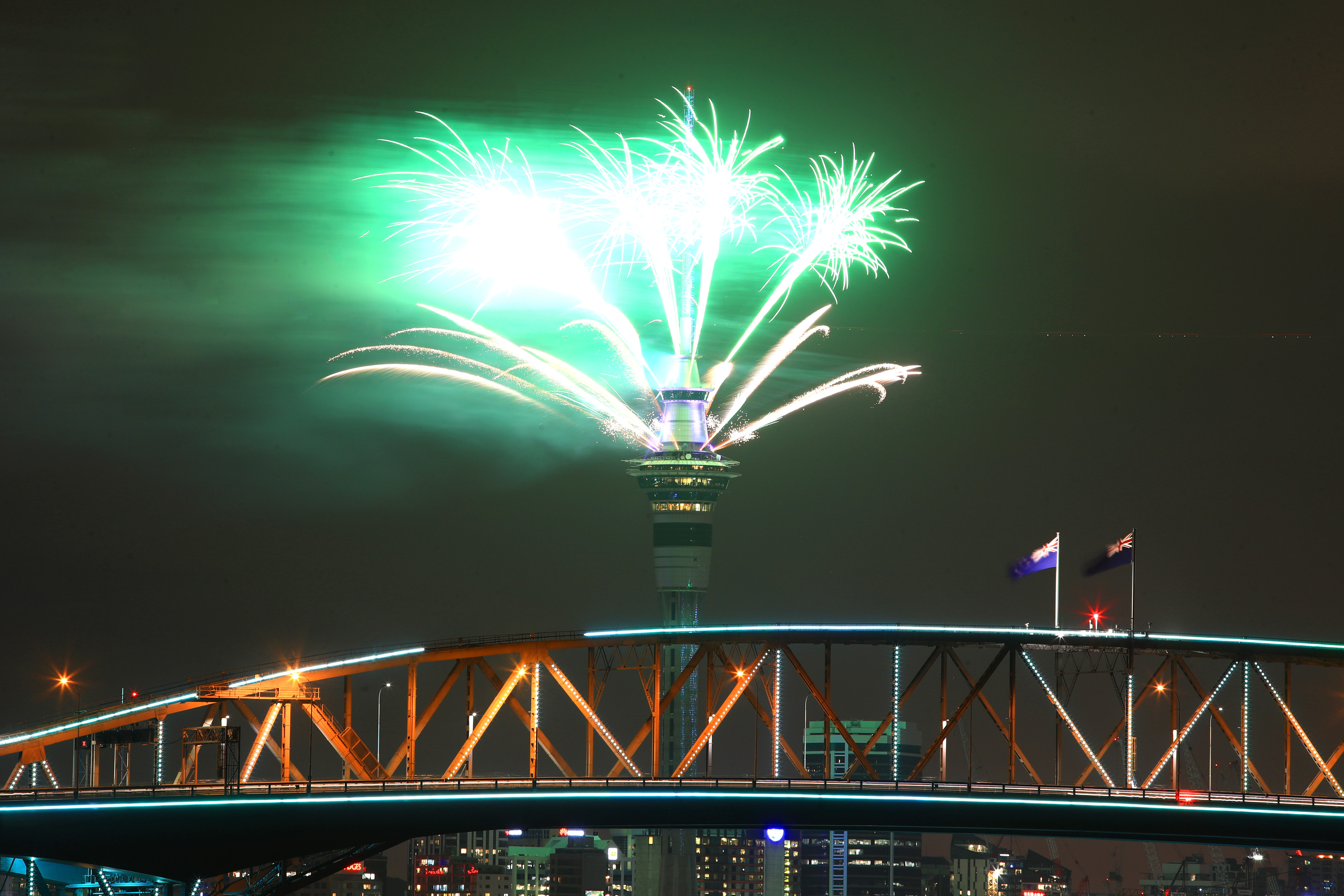 Fireworks are seen exploding from the Sky Tower with the Auckland Harbour Bridge in the foreground during the Auckland New Year