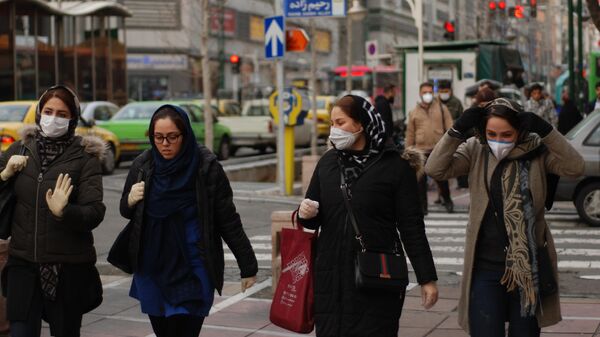 Жители Тегерана идут по одной из центральных улиц в медицинских масках