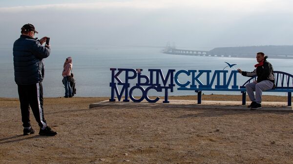 Люди фотографируются напротив Крымского моста