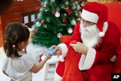 A man dressed as Santa Claus gives a present to a child on Christmas day at a shopping mall in Petaling Jaya, Malaysia, Dec. 25, 2017.