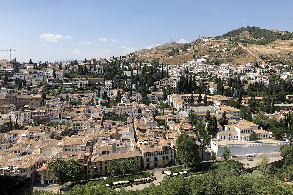 С крепости Альгамбра видно дома с белыми стенами и овальными окнами. Они напоминают здания в арабских странах